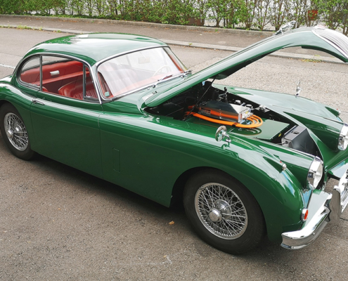 Jaguar XK 150, halbseitliche Ansicht, das Fahrzeug steht mit offener Haube da.