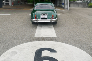 Ein grüner Jaguar XK 150 steht auf einer Prüfbahn des Strassenverkehrsamtes Zug. Ansicht von Hinten auf das Auto. Man erkennt die Bahnnummer 6 im Bild unten, etwas angeschnitten.