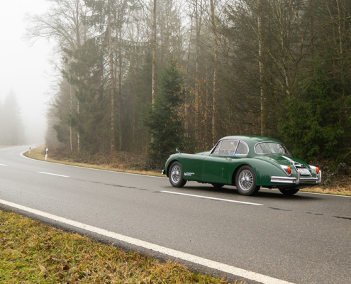 Jaguar on misty country road Elektrischer Jaguar XK150 fährt auf Landstrasse im Nebel