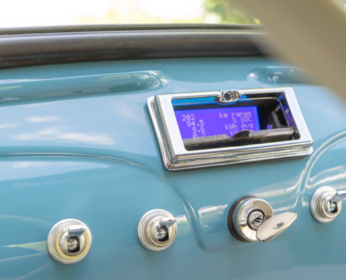 The display can be concealed behind the original ashtray flap Ansicht auf das Armaturenbrett eines Fiat 500, in Wagenfarbe (mittelblau) lackiert. Dort, wo früher der Aschenbecher ist, ist ein kleiner Display versteckt, der Informationen wie Verbrauch oder Restreichweite anzeigt.
