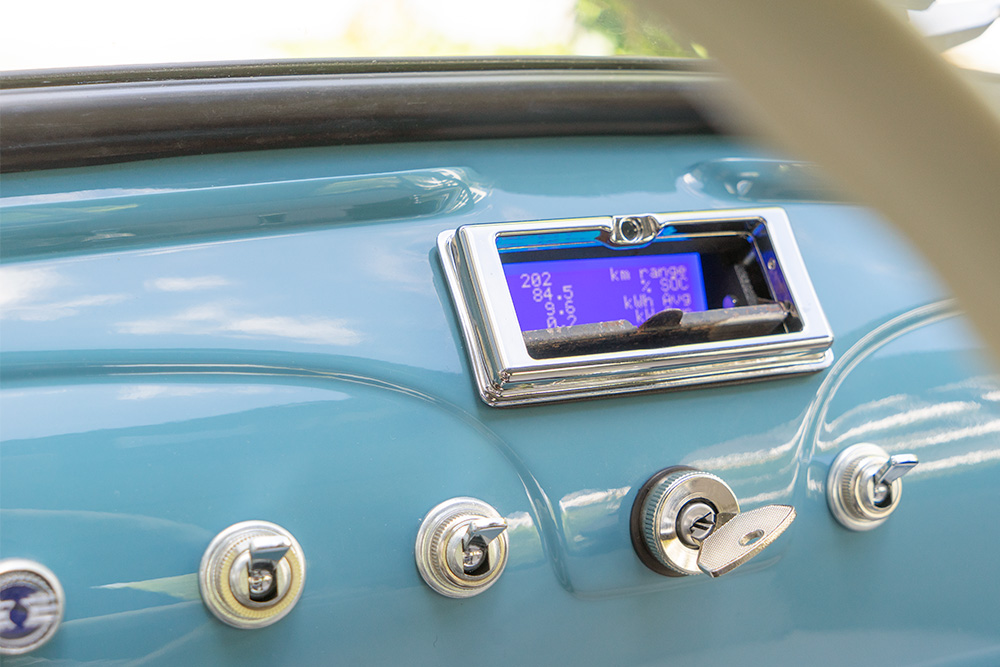 The display can be concealed behind the original ashtray flap Ansicht auf das Armaturenbrett eines Fiat 500, in Wagenfarbe (mittelblau) lackiert. Dort, wo früher der Aschenbecher ist, ist ein kleiner Display versteckt, der Informationen wie Verbrauch oder Restreichweite anzeigt.