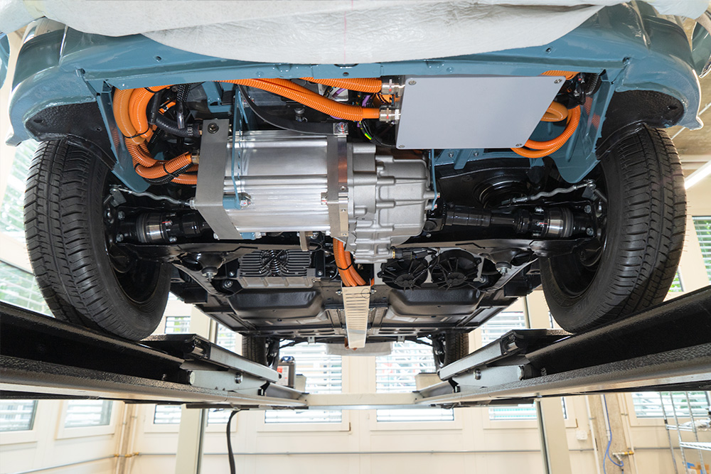 View from below showing the motor Blick auf den Unterboden eines Fahrzeugs. Man sieht Kabel, einen Elektromotor mit Getriebe/Differential.