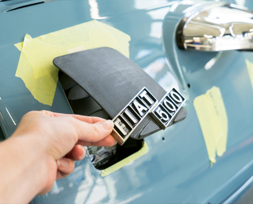 At the rear of the vehicle is a new charging flap, which is still in development Eine Öffnung am Heck des blau lackierten Fiat 500, die mit einer Klappe aus Kunststoff verschlossen werden kann. Im Bild ist diese halb geöffnet, an ihr ist das Logo "Fiat 500" angebracht.