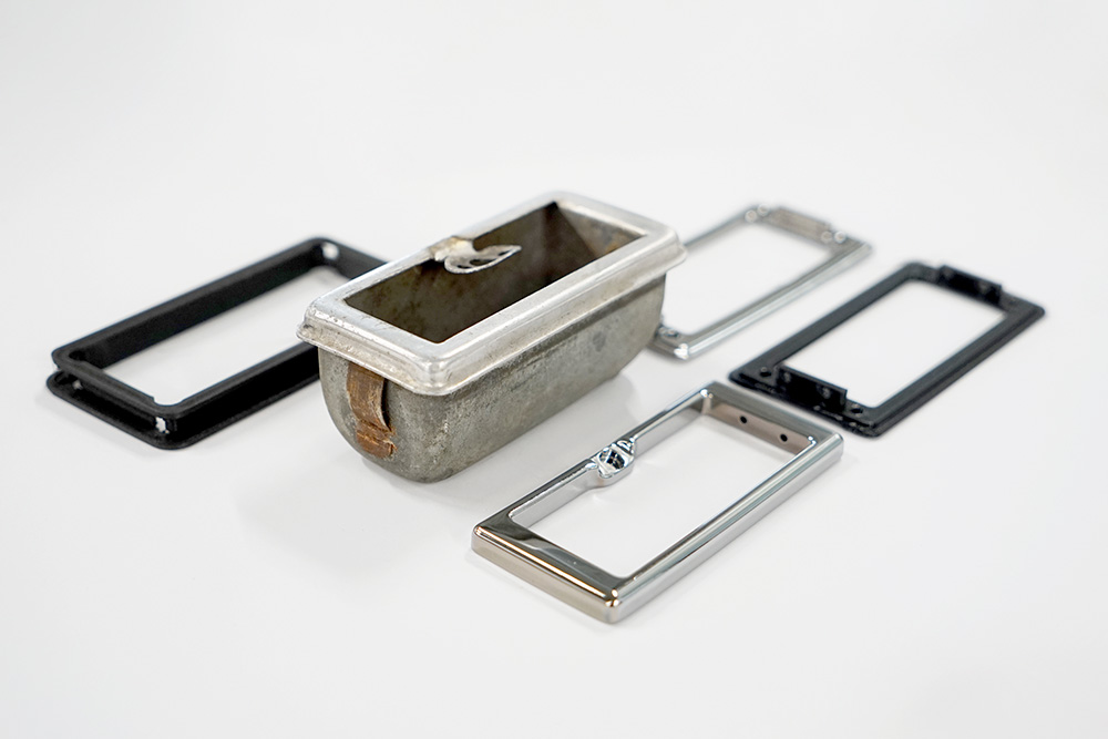 The ashtray is no longer needed. In its place, a display will be installed; the frame is a replica of the ashtray’s frame Ein Aschenbecher aus einem Fahrzeug, ausgebaut. Rund herum 3D-gedruckte Teile, die den Rahmen des Aschenbechers nachbilden. 2 der 4 Teile sind verchromt, die anderen roh, aus schwarzem Kunststoff.